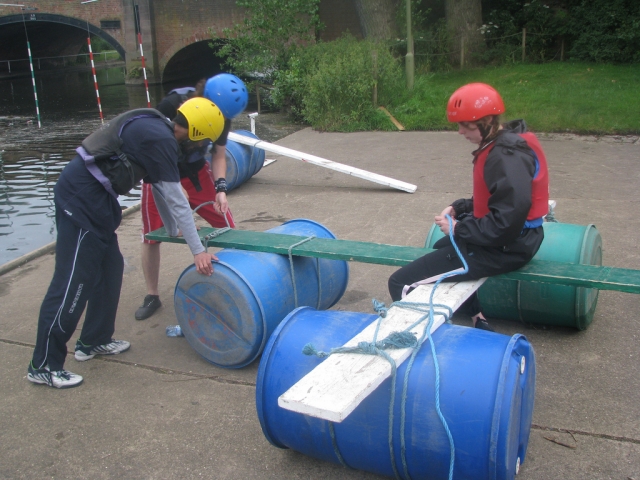 The team builds the bridge by using barrels, ropes and planks